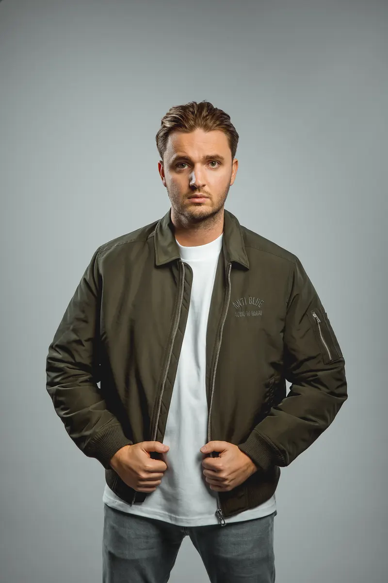 The Herbalist in an olive bomber jacket and white T-shirt, studio portrait